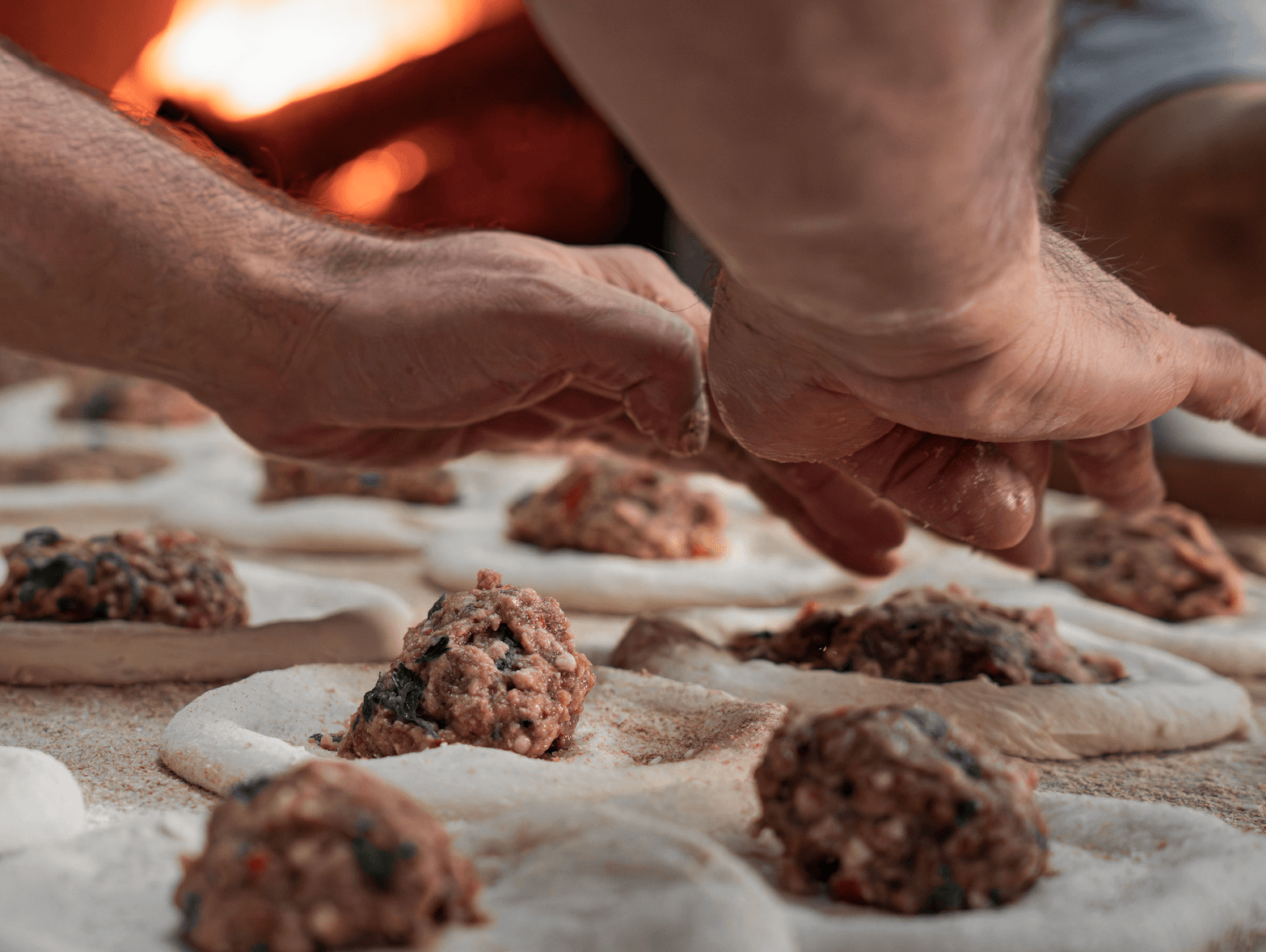Hands carefully folding freshly prepared filled pastries